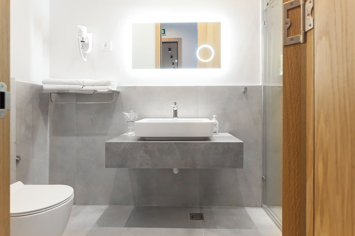 Un baño moderno con lavamanos empotrado, espejo y retrete.