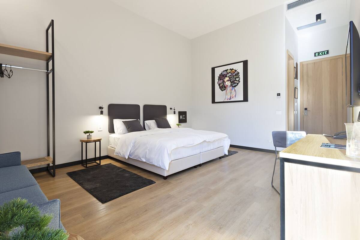 Een moderne slaapkamer met een bed, nachtkastjes, een bureau en een stoel.
