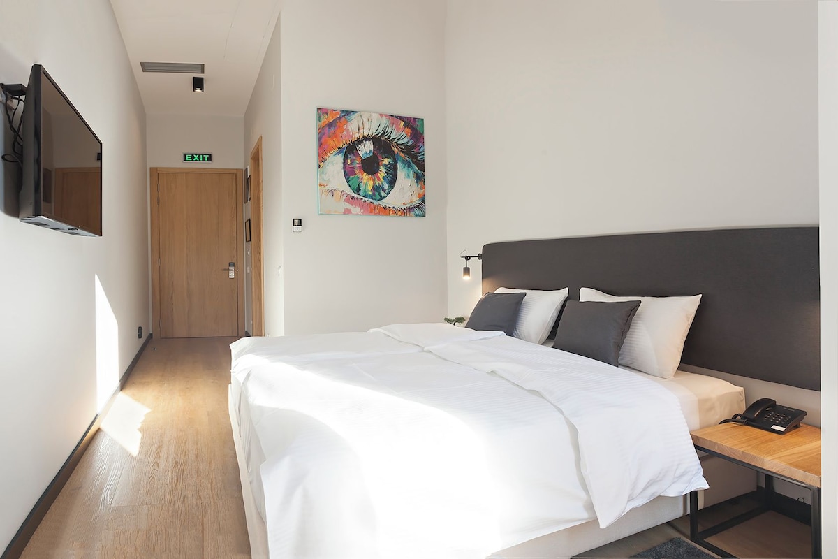 Une chambre d’hôtel avec un grand lit, une table de chevet avec un téléphone et un tableau au mur.