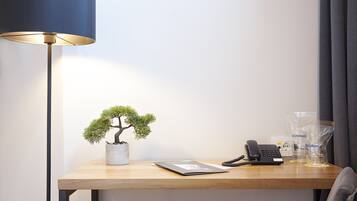 A desk with a bonsai tree, a phone, and a lamp.