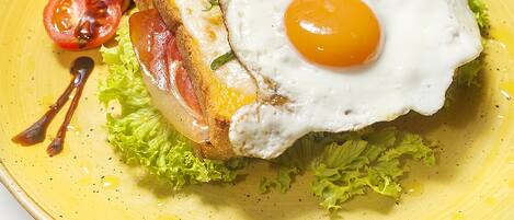 A plate with a fried egg, bacon, lettuce, and a cherry tomato.