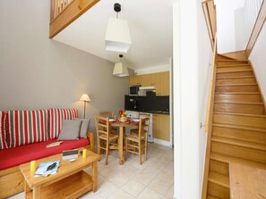 A compact living space with a sofa, dining table, chairs, a kitchen area, and a staircase. - Holiday Home in Montignac near Lascaux II (Montignac)