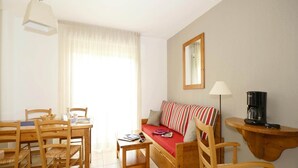 A cozy living area with a sofa, a dining table with chairs, a coffee machine, and a mirror on the wall. - Holiday Home in Montignac near Lascaux II (Montignac)
