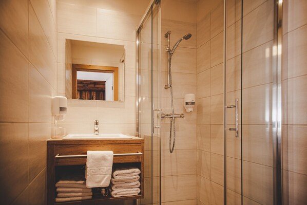 A modern bathroom with a glass-enclosed shower, a wooden vanity with a sink, and a mirror above the vanity.