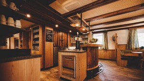 A cozy, rustic bar area with wooden floors and shelves filled with glasses and bottles. - Gschoadwirt (Sankt Aegyd am Neuwalde)