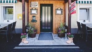 A building with a wooden facade, a green door, and two potted plants at the entrance. - Gschoadwirt (Sankt Aegyd am Neuwalde)