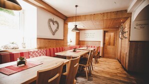 A restaurant with wooden walls and a heart-shaped decoration on the wall. There are wooden tables and chairs, and a sign that reads "Gastgarten WC". - Gschoadwirt (Sankt Aegyd am Neuwalde)