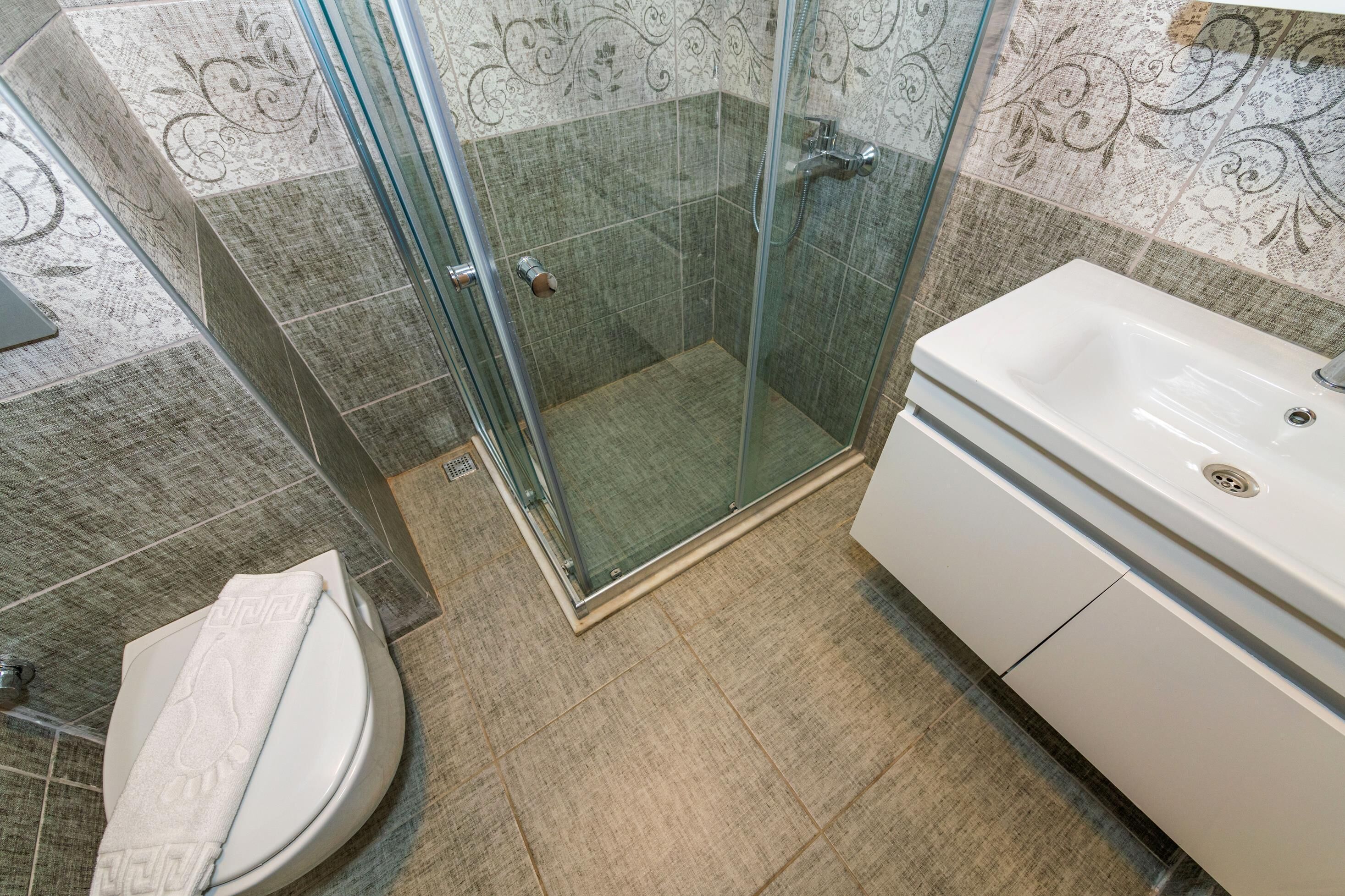 A bathroom with a glass-enclosed shower, a white toilet, and a white sink.