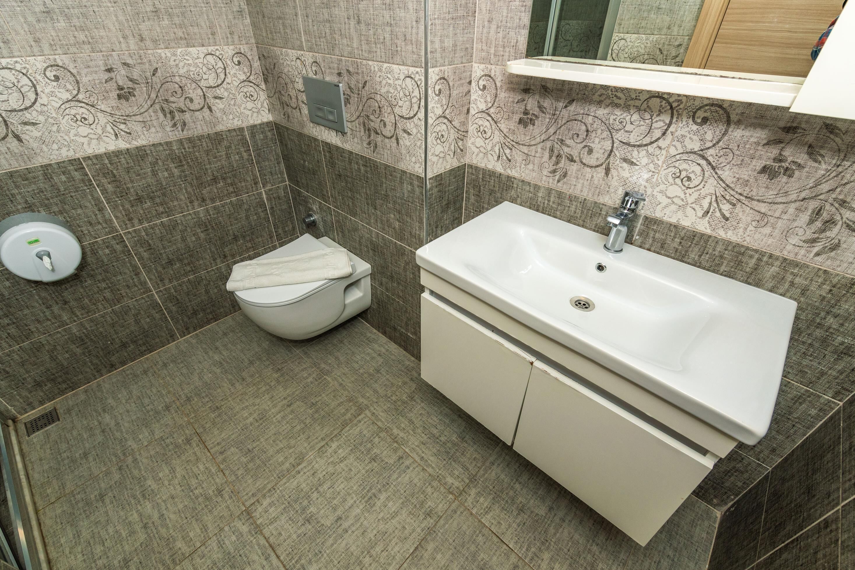 Un baño con inodoro, lavamanos y secamanos.