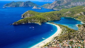 A coastal town with a beach, clear blue waters, and green hills.