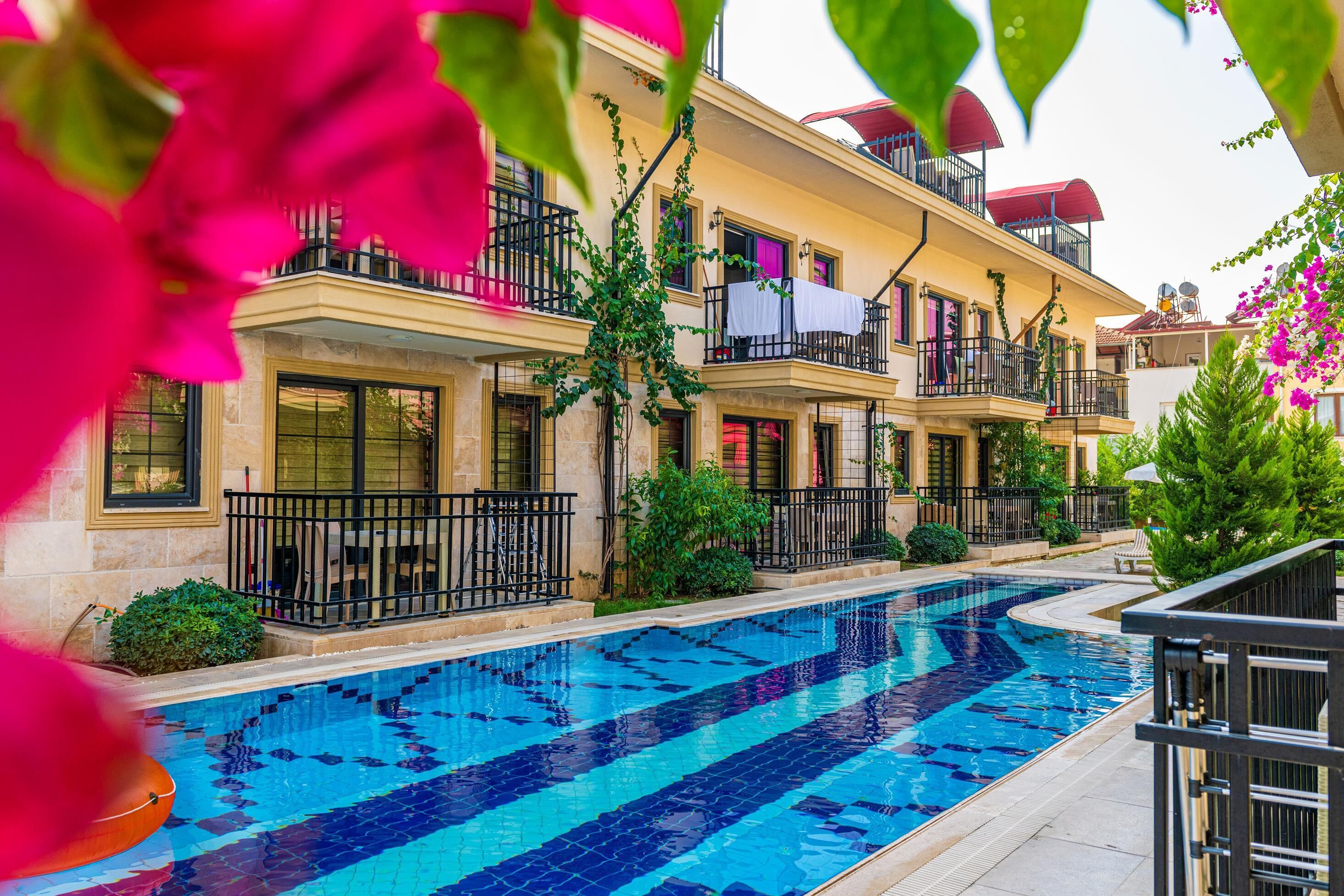 A swimming pool with a tiled edge, surrounded by a building with balconies and windows.