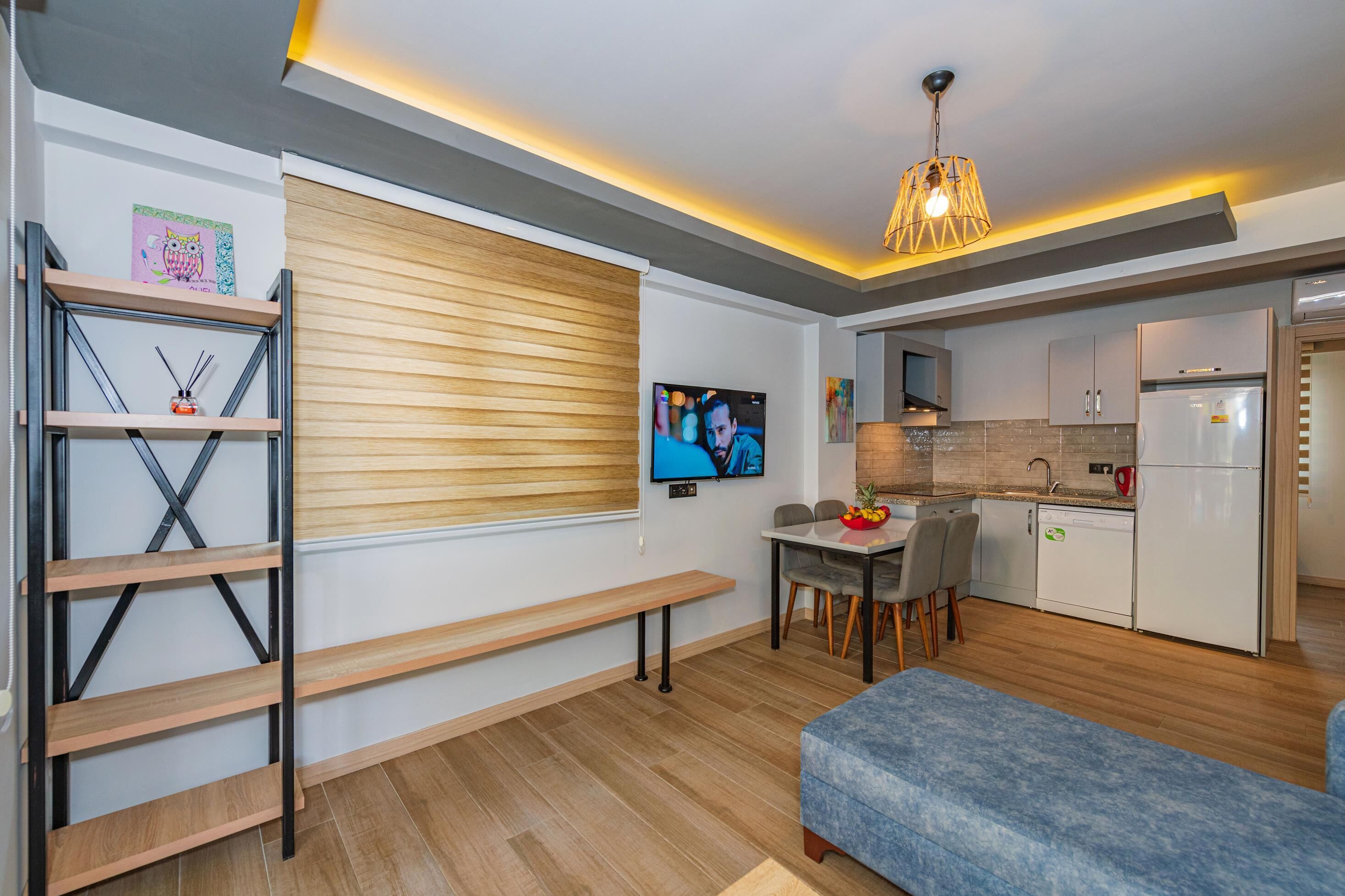 A modern kitchen with a built-in oven, a dining area with a table and chairs, and a TV mounted on the wall.
