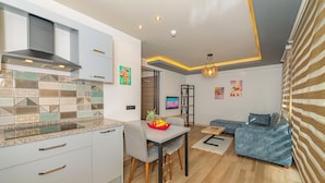 A modern kitchen with a dining area, a sofa, and artwork on the walls.