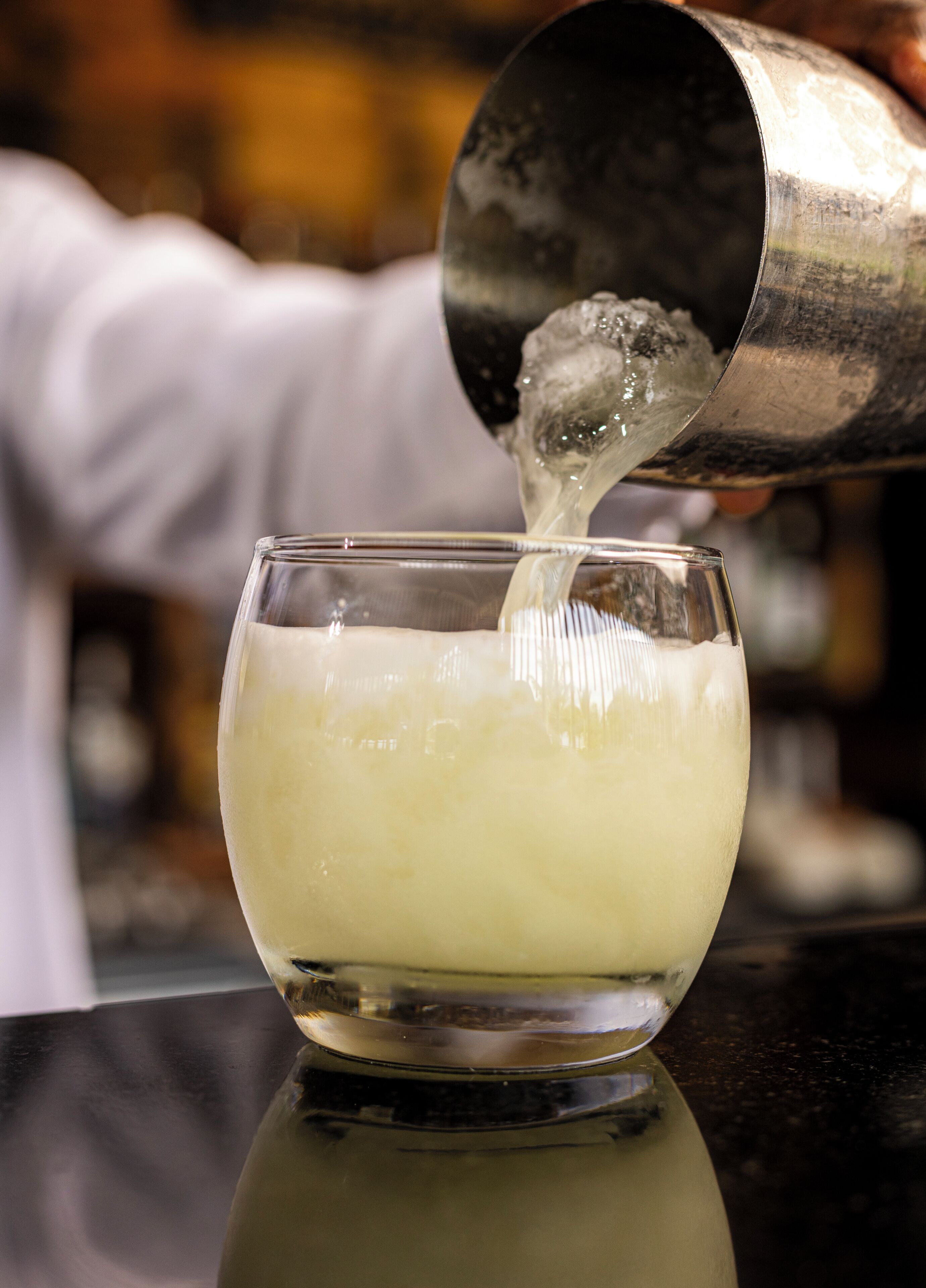 A person pouring a clear liquid into a glass.