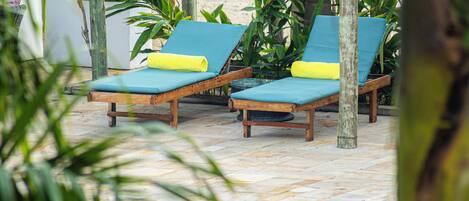 A poolside area with lounge chairs and a wooden pergola.