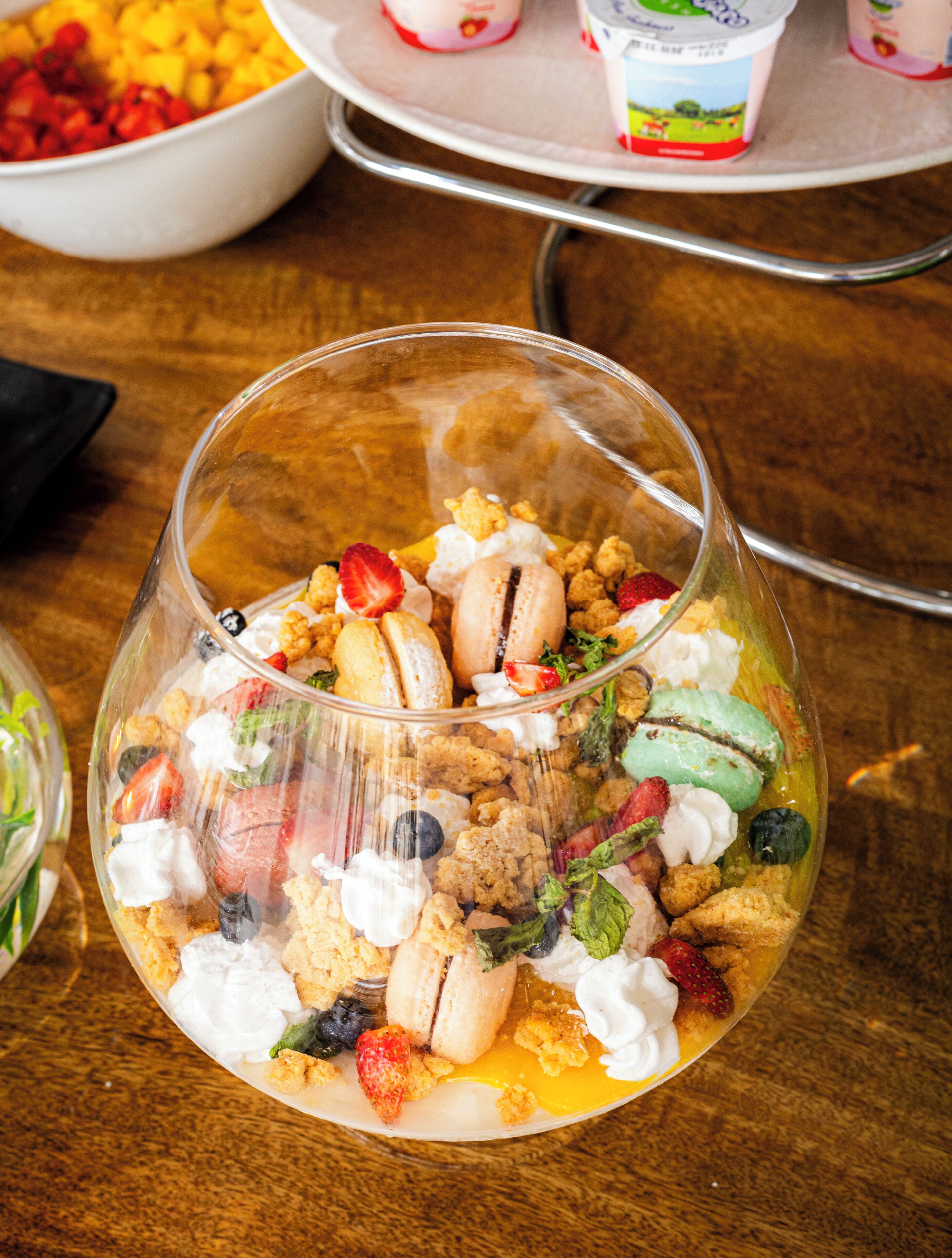A dessert in a clear glass bowl with various toppings.