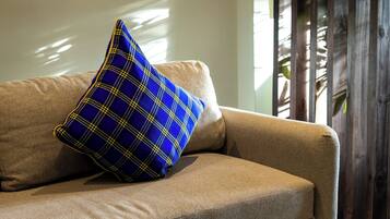 Un sofá color beige con un cojín azul de estampado escocés y una mesa redonda con una bandeja de diseño azul y blanco.