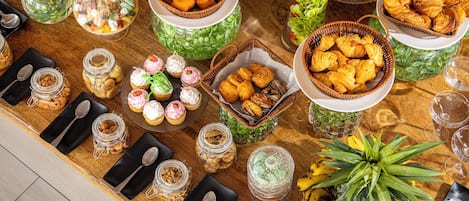 A buffet table with various food items, including pastries, fruits, and desserts.