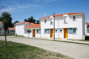 A row of white buildings with red-tiled roofs, each with a single door and windows. - Apartment in France near the Beach (Saint Brevin L'océan)