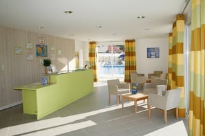 A reception area with a green counter, seating, and a view of the outside.