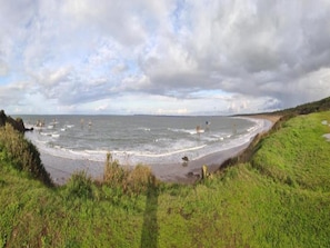 A coastal landscape with a sandy beach, grassy areas, and the sea.