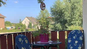 A balcony with two chairs and a table, a potted plant, and a decorative sign. - Vacation apartment Bad Wilsnack (Bad Wilsnack)