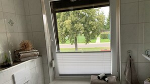 A bathroom with a window, a towel rack, a sink, and a toilet. - Vacation apartment Bad Wilsnack (Bad Wilsnack)