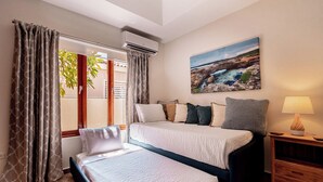 Camera d'albergo con due letti, un quadro, una lampada e un condizionatore d'aria.
