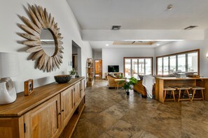 A spacious living area with a wooden cabinet, a decorative mirror, and a seating area with a table and chairs. - Pool Oasis: 3BR Home w/ Patio near Arashi Beach (Noord)