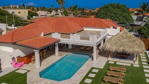 Una proprietà residenziale con piscina, area relax all'aperto e una struttura con tetto di paglia.