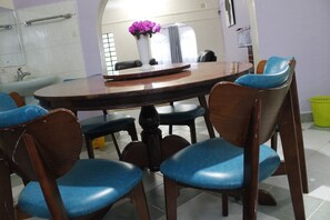 A dining area with a round wooden table surrounded by blue cushioned chairs. - Sweet Apple Mansion Naivasha (Naivasha)