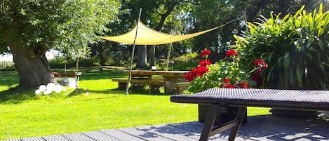 Un patio jardín con mesa y sillas, rodeado de follaje y un árbol.