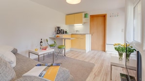 A compact living space with a kitchenette, a dining area, and a seating area with a sofa and a coffee table.