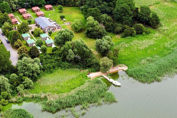 An aerial view of a lakeside property with multiple buildings, a dock, and surrounding greenery.