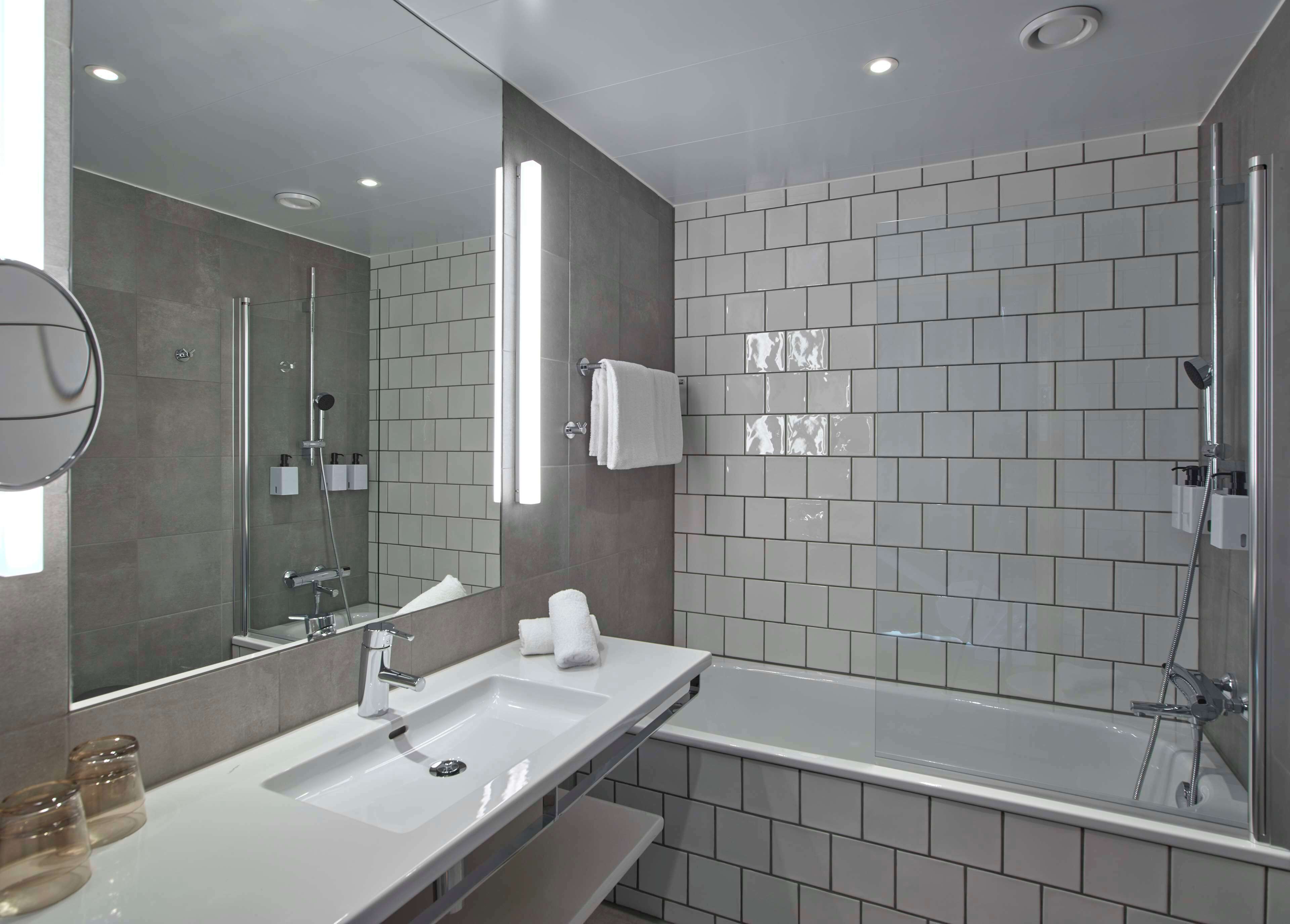 Ein modernes Badezimmer mit großem Spiegel, Waschbecken, Badewanne und Dusche.