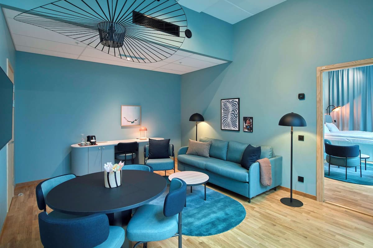 A modern living room with a round table, blue sofas, and a ceiling fan.