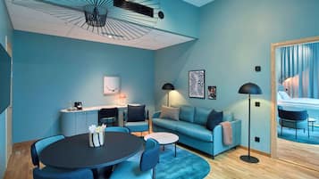 Een moderne woonkamer met een ronde tafel, blauwe banken en een plafondventilator.