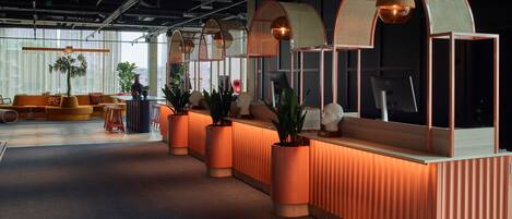 A modern reception area with a curved desk, potted plants, and a view of the city.