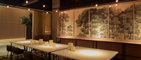 Un salón de conferencias con largas mesas, sillas y velas.
