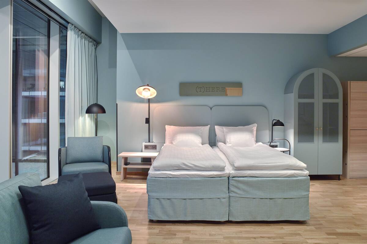 A modern bedroom with a double bed, a sofa, a desk, and a lamp.