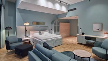 Un dormitorio moderno con cama, mesitas de noche, un escritorio y un área de descanso.