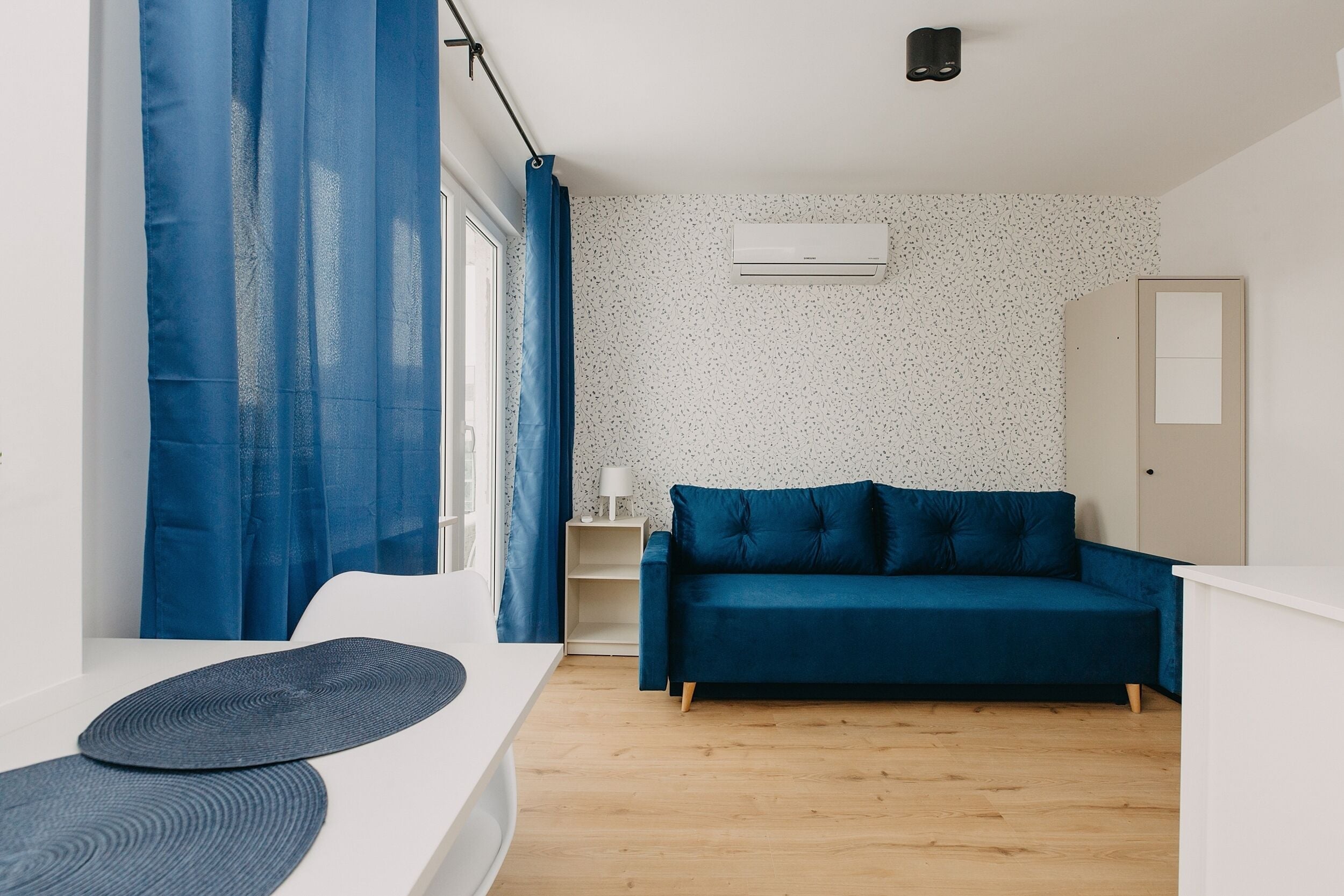 A modern room with a blue sofa, a white desk, and a small side table.