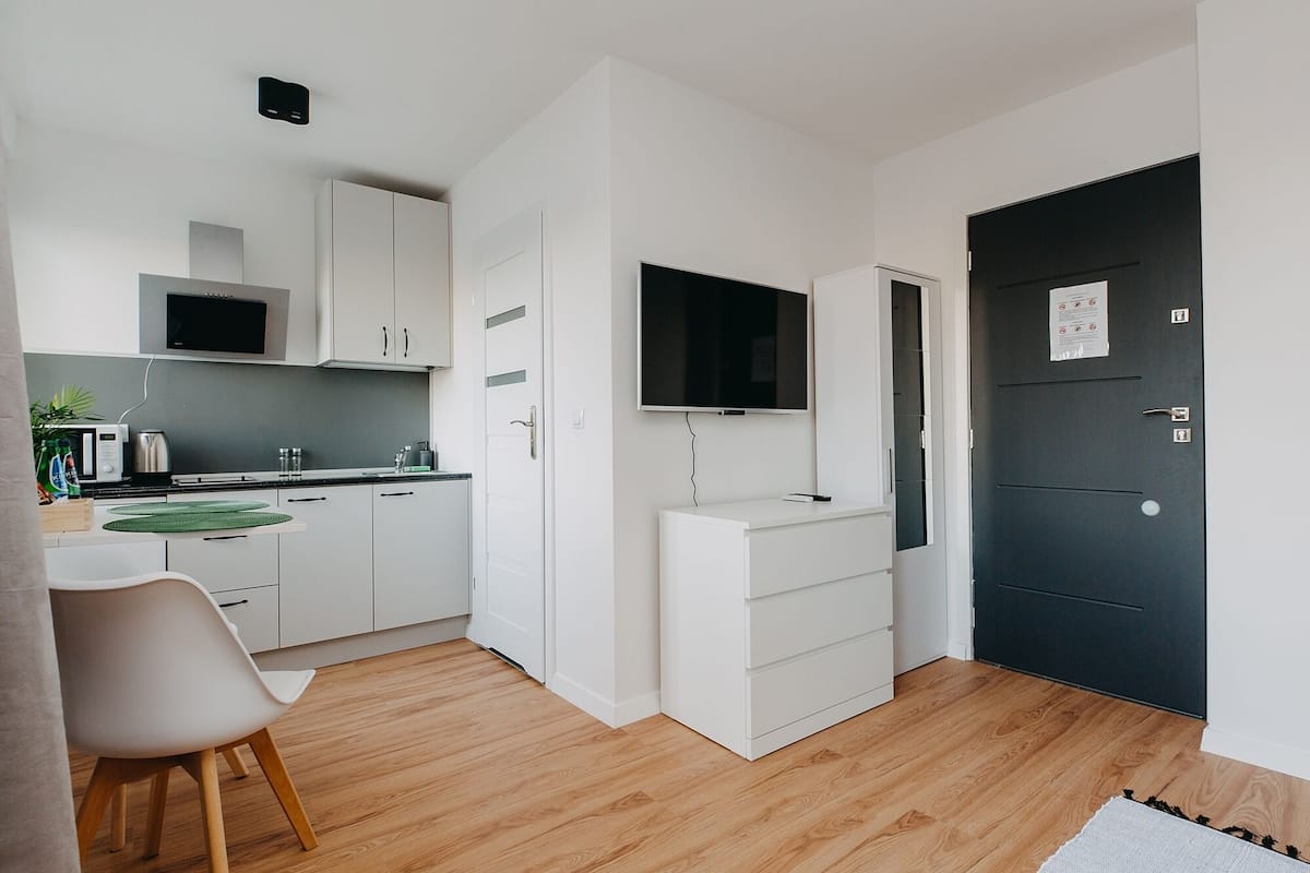 A compact kitchen with white cabinets, a microwave, and a TV mounted above the counter.
