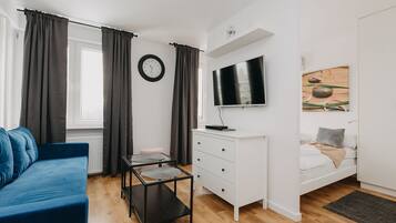Een moderne slaapkamer met een bed, een televisie, een bureau en een blauwe bank.