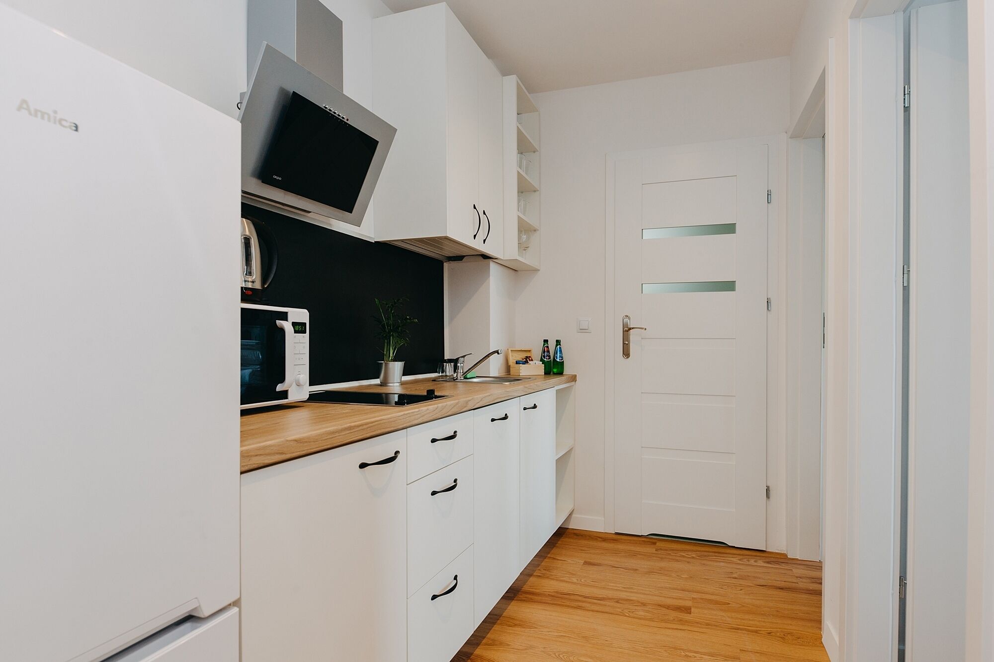 A compact kitchen with white cabinets, a microwave, a stove, and a sink.