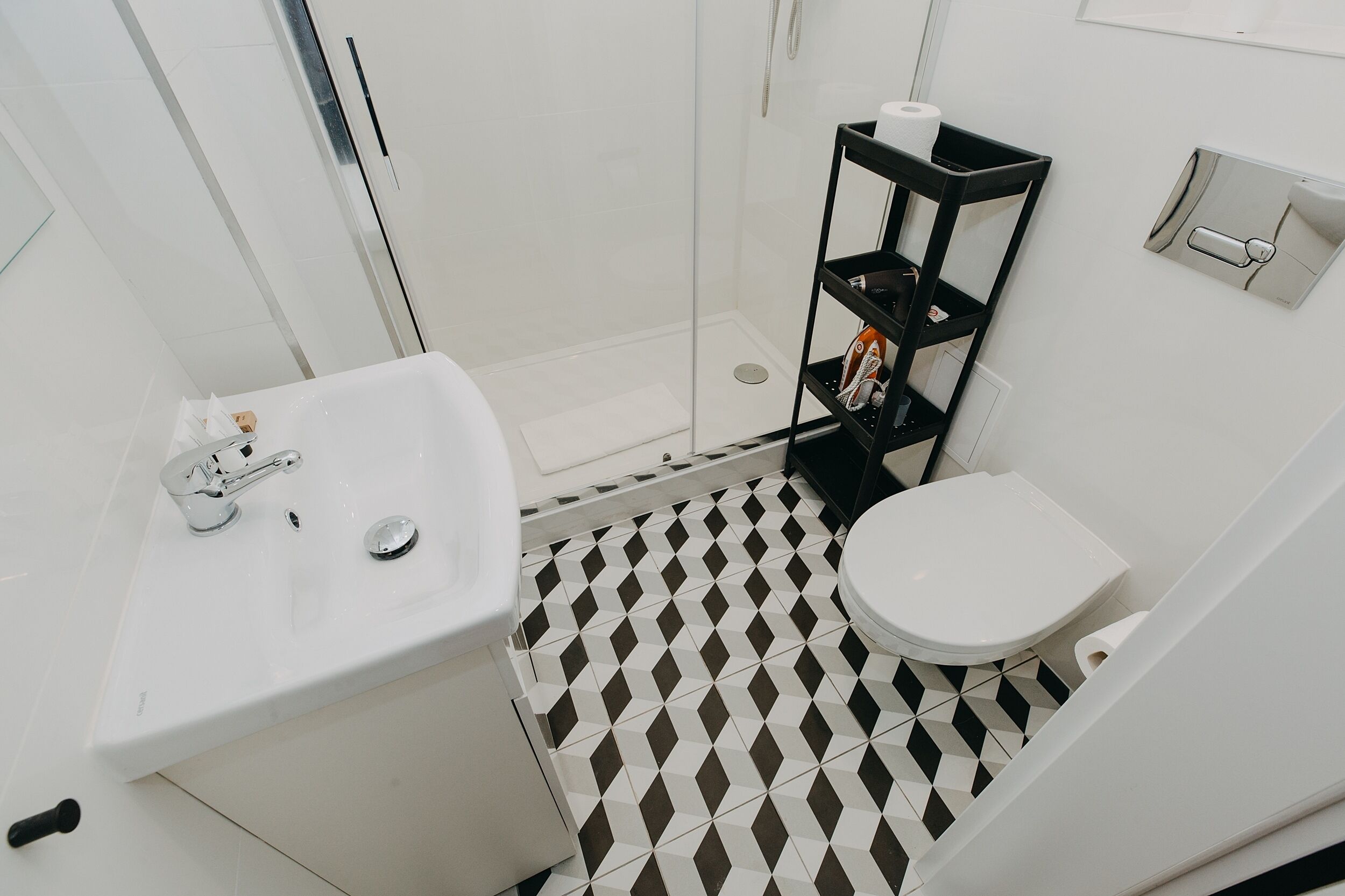A bathroom with a white sink, toilet, and a shower area.