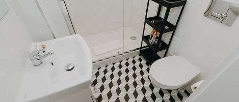A bathroom with a white sink, toilet, and a shower area.