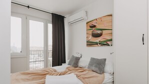 A bedroom with a bed, a window with curtains, an air conditioning unit, and a wall-mounted artwork. - ShortStayPoland Panska (Warsaw)