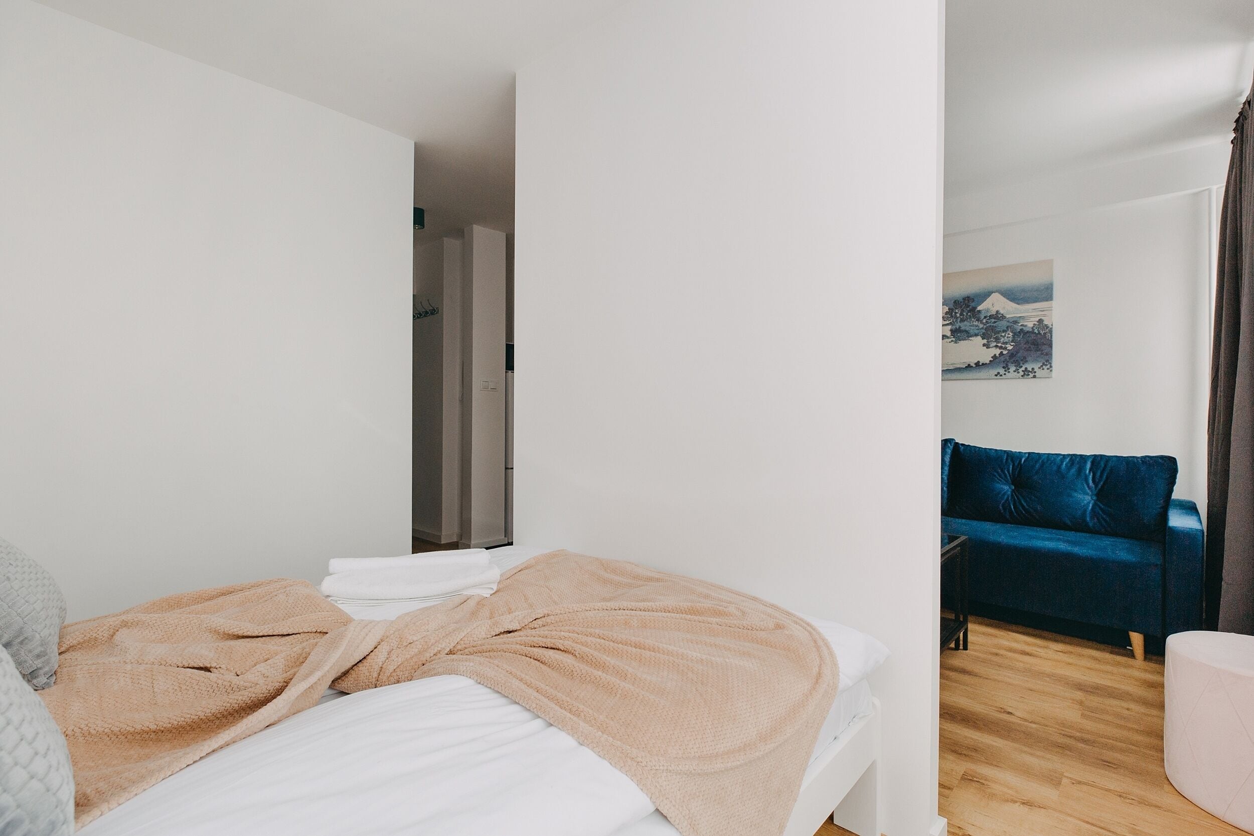 Ett sovrum med en säng, en blå soffa och en tavla på väggen.