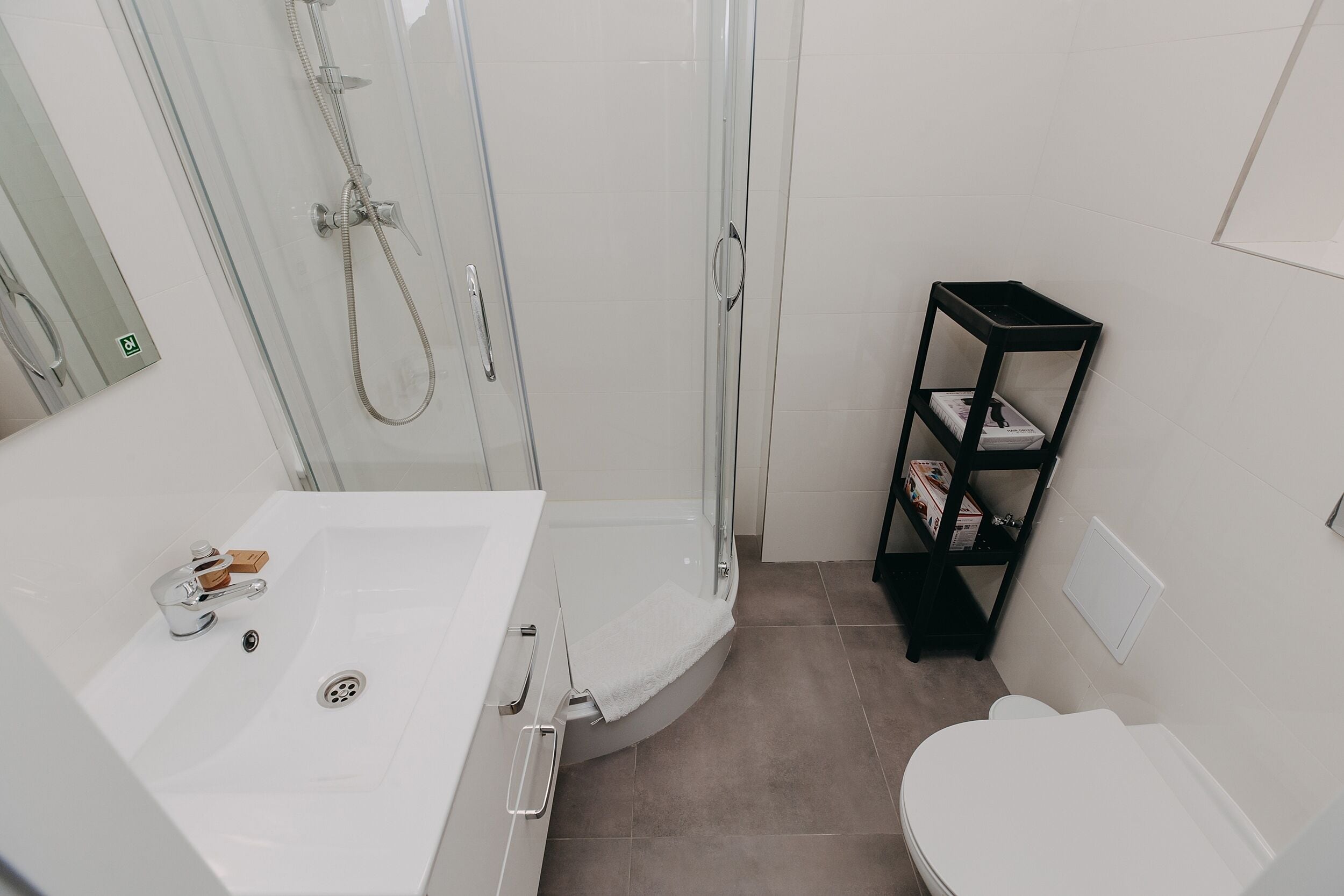 A compact bathroom with a glass-enclosed shower, a white sink with a faucet, and a toilet.